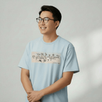 Person wearing a light blue t-shirt with text and graphics on a plain background