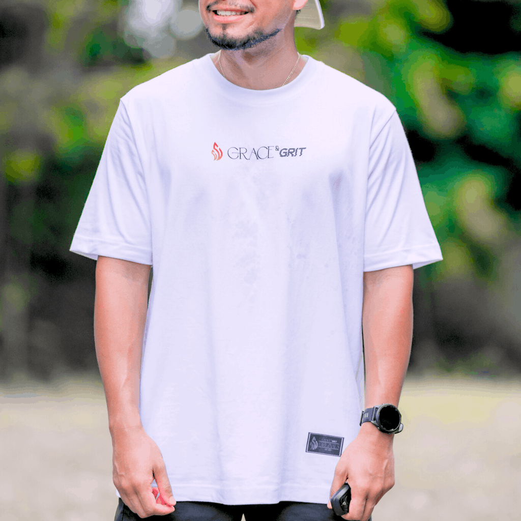 Person wearing a white t-shirt with 'Grace & Grit' logo outdoors