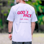 Person wearing a white t-shirt with text that says 'GOD'S PACE not mine.' and 'Ecclesiastes 3:11' below, standing outdoors