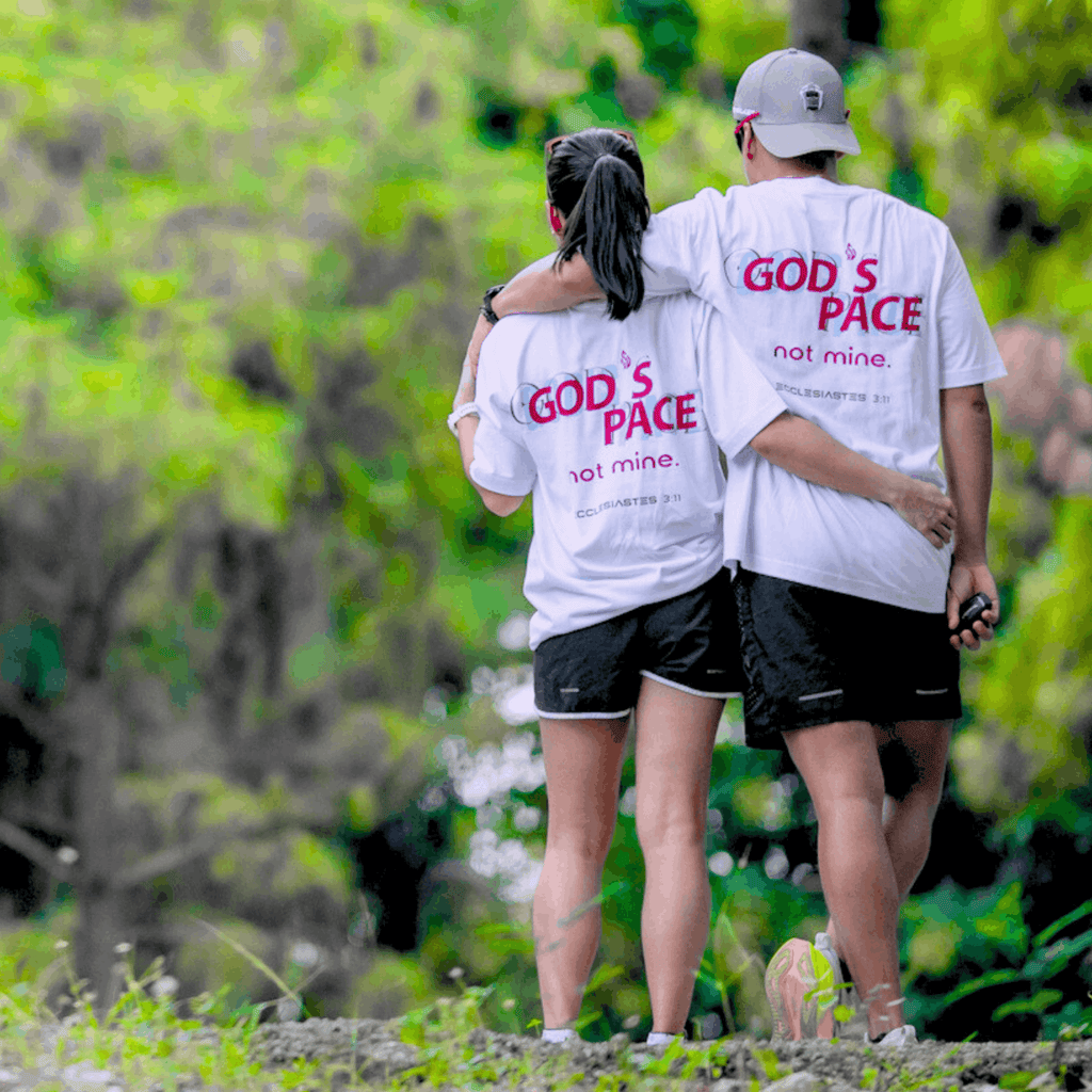 Two people wearing white t-shirt with text that says 'GOD'S PACE not mine.' and 'Ecclesiastes 3:11' below, standing close together outdoors
