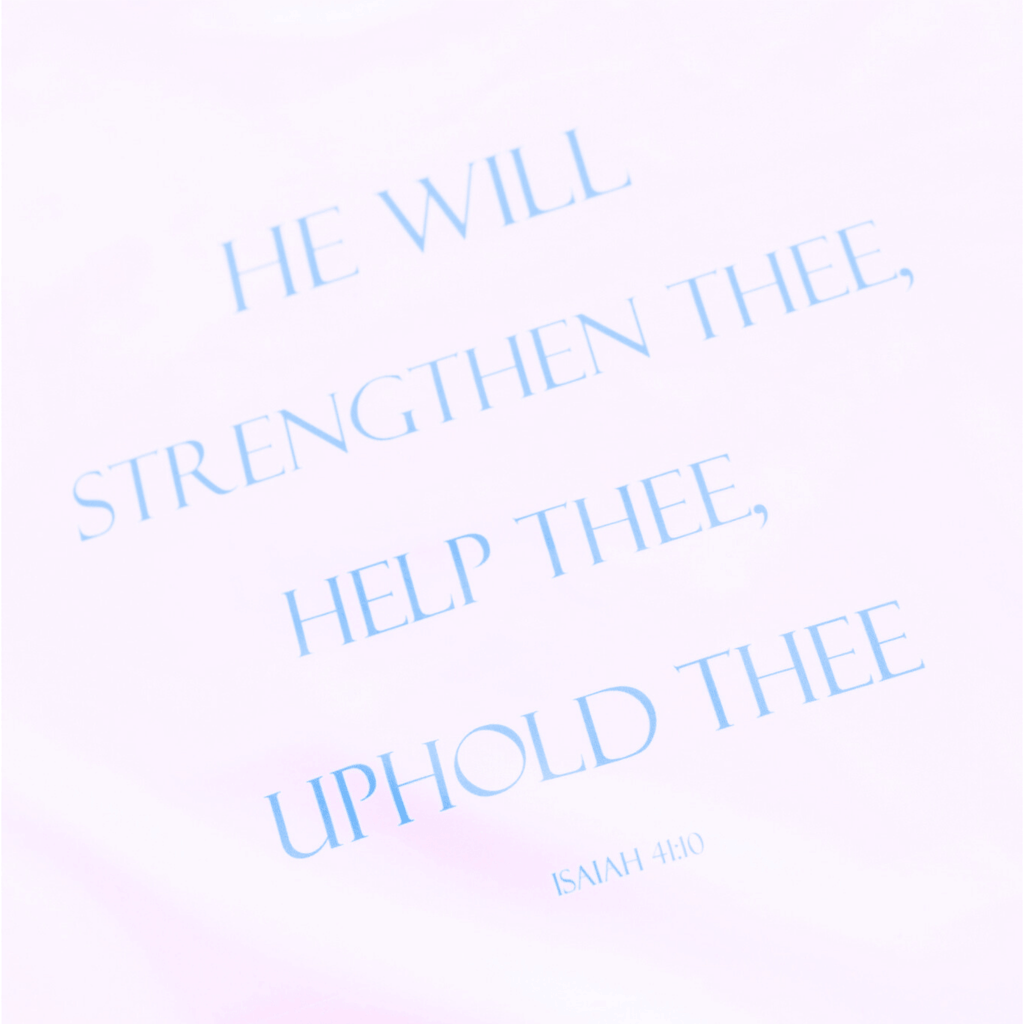 Close up picture of a white t-shirt text that says 'HE WILL STRENGTHEN THEE, HELP THEE, UPHOLD THEE ISAIAH 4:10'