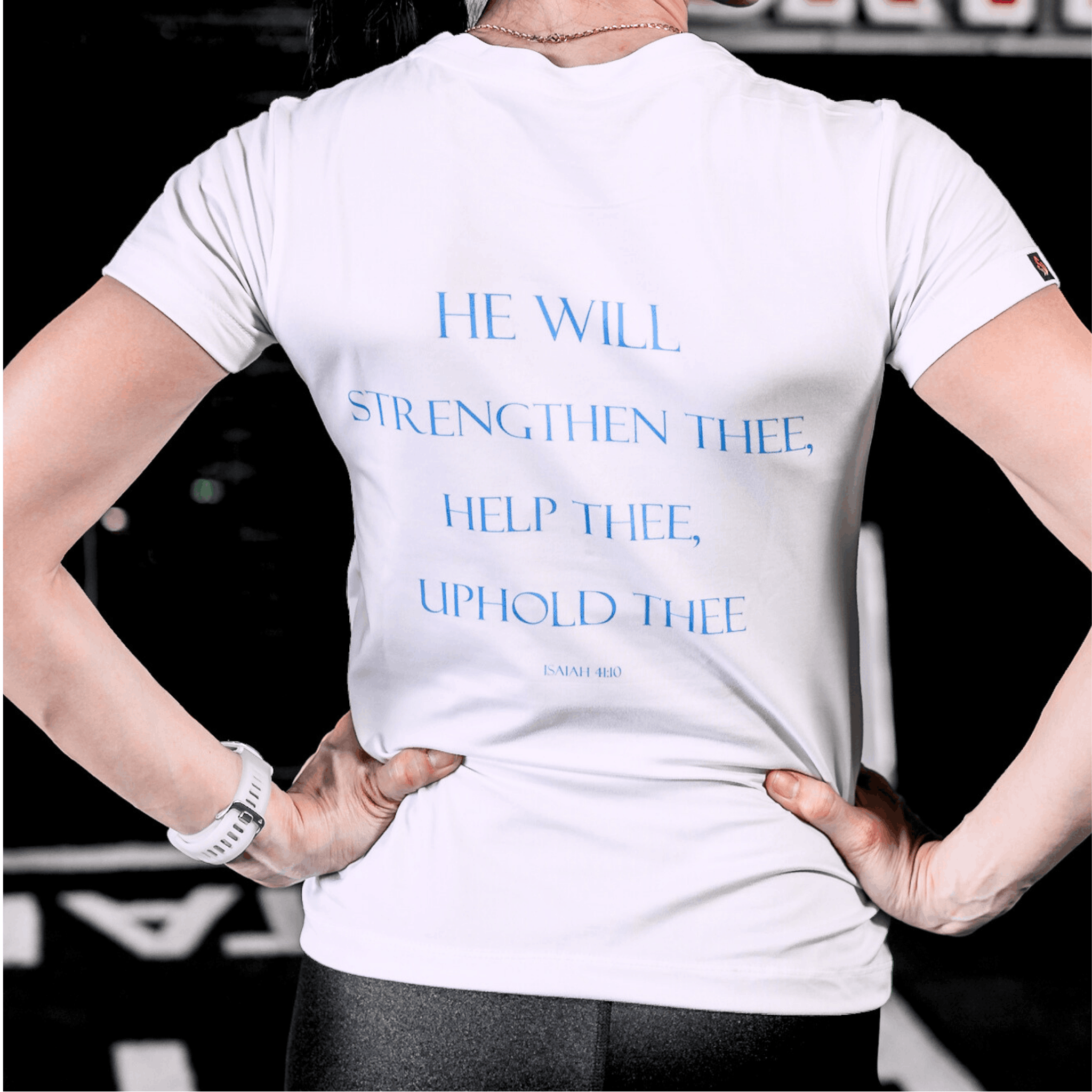 Woman wearing a white t-shirt text that says 'HE WILL STRENGTHEN THEE, HELP THEE, UPHOLD THEE ISAIAH 4:10'