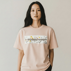 Person wearing a peach t-shirt with a graphic design on a plain background