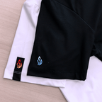 Close-up of a black and white t-shirt with logos on their sleeve, on a wooden surface