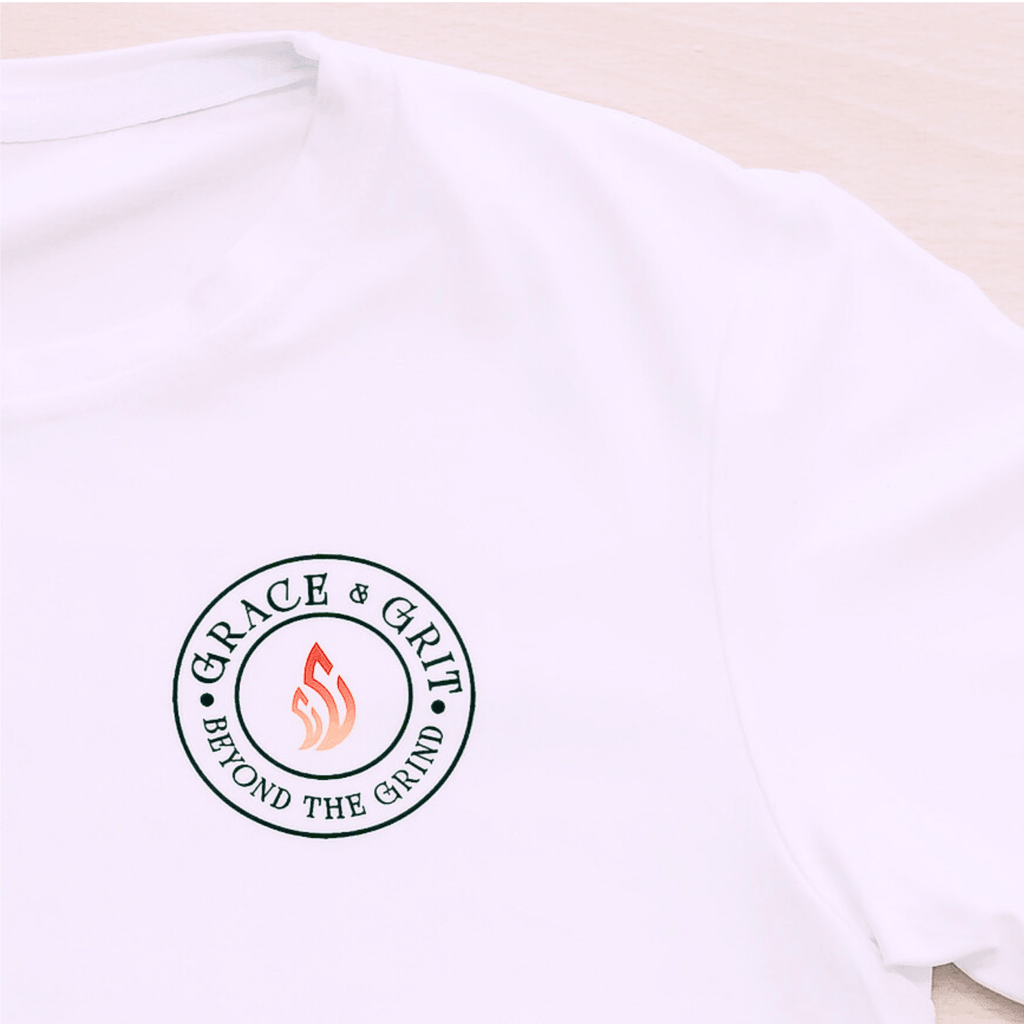 White t-shirt with 'Grace & Grit' logo on a light wooden surface