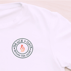 White t-shirt with 'Grace & Grit' logo on a light wooden surface
