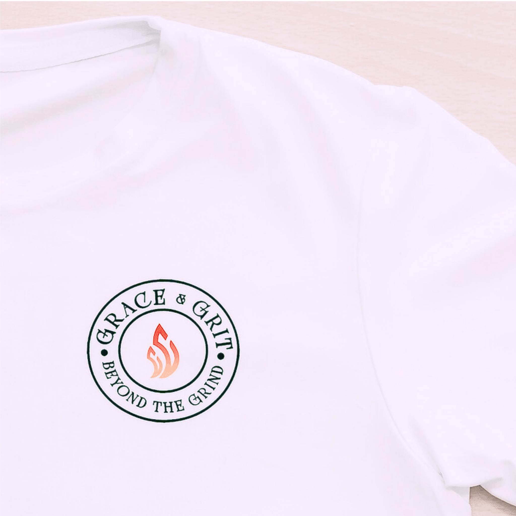 White t-shirt with 'Grace & Grit' logo on a light wooden surface