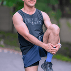 A gentleman stretching outdoors wearing a mint and black singlet