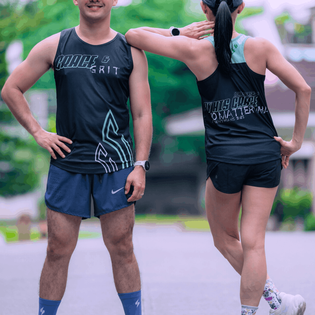 Two runners  wearing a mint and black running singlet. Standing outdoors while the woman is leaning her elbow on to the gentleman.
