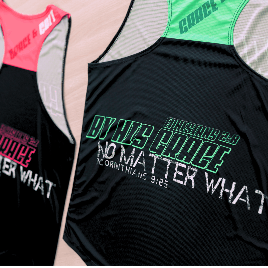 Two black running singlets with vibrant colored text and design (pink and black, mint and black) on a table