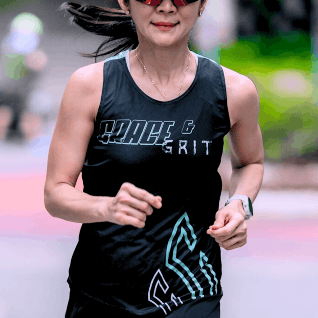 Woman running outdoors wearing a mint and black running singlet with graphics and text.