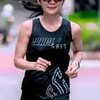 Woman running outdoors wearing a mint and black running singlet with graphics and text.