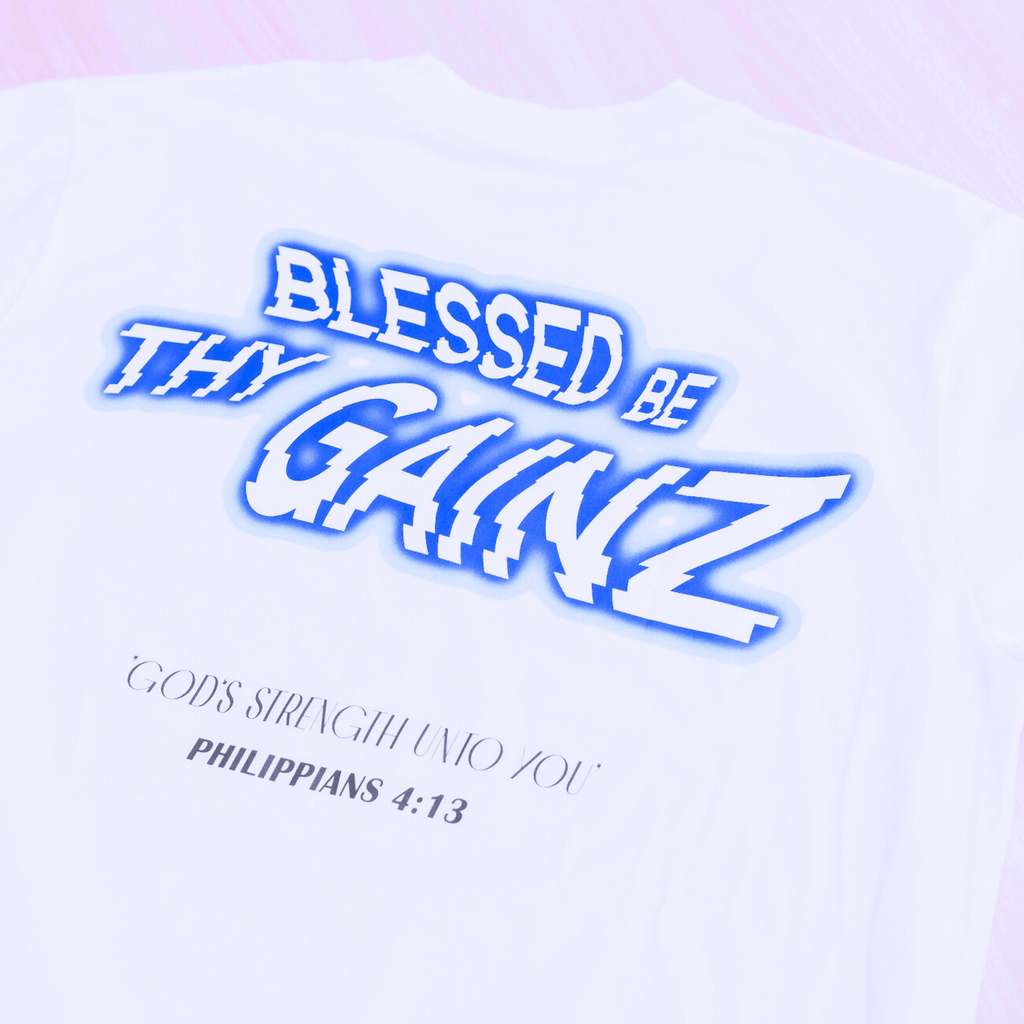 A white shirt with a print that says 'BLESSED BE THY GAINZ' and "'GOD'S STRENGTH UNTO YOU' PHILIPPIANS 4:13".