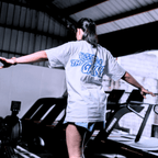 A woman in the gym wearing a white t-with a print that says 'BLESSED BE THY GAINZ' and "'GOD'S STRENGTH UNTO YOU' PHILIPPIANS 4:13".