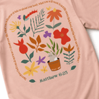 Peach t-shirt with floral design and 'Matthew 6:25' text on a white background