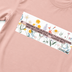 Peach t-shirt with a graphic of flowers and text on a white background